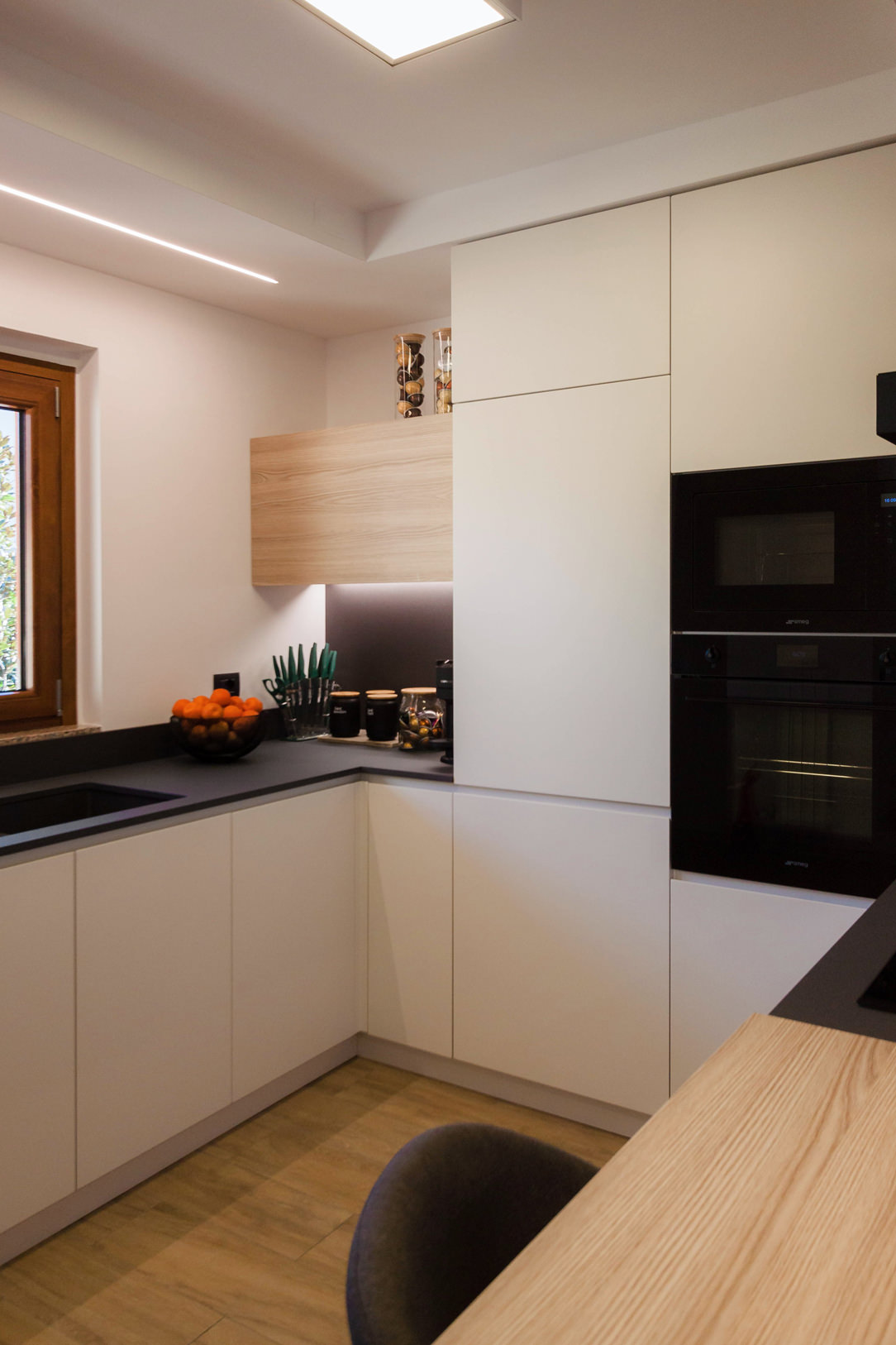 Corner kitchen with peninsula in shades of grey lacquered doors oak wood top anthracite